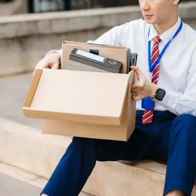 Person with their things packed in the box, sitting on stairs